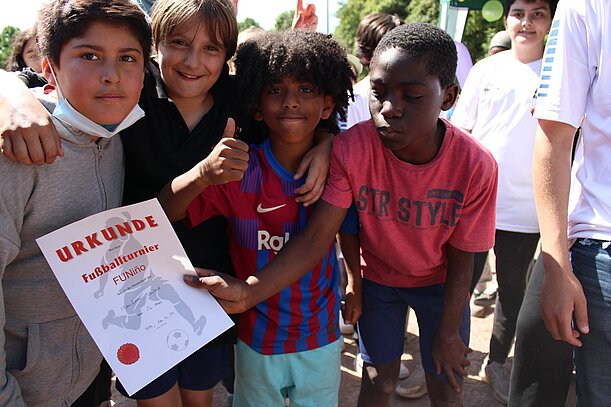 Vier fröhliche Grundschüler mit Urkunde vom Fußballturnier
