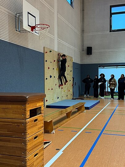 Schülerin klettert an der Kletterwand der Sporthalle beim Sportfest
