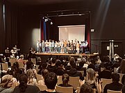 Voll besetzte Aula beim Musikfest mit Sängerinnen und Sängern auf der Bühne