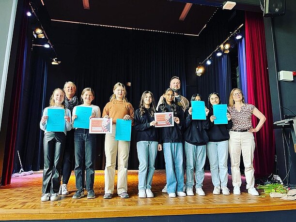 Schülerinnen und Schüler mit Urkunden auf der Bühne zum Abschluss der Projektwoche