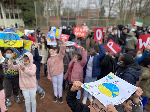 Kinder zeigen Friedenszeichen in Ukraine-Farben bei der Aktion gegen Krieg