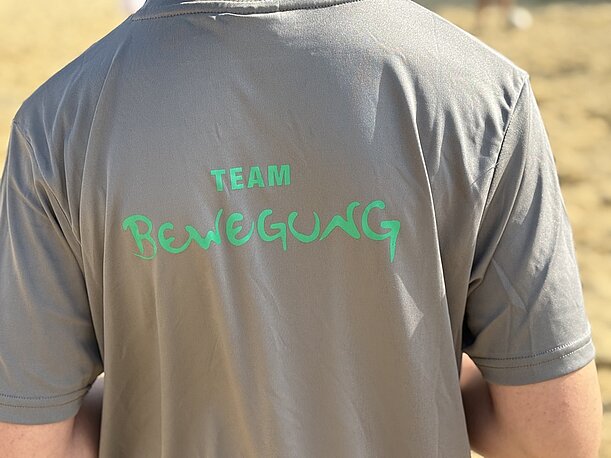 Rückenaufdruck „Team Bewegung“ auf einem grauen T-Shirt