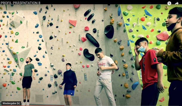 Jugendliche in einer Kletterhalle vor bunter Boulderwand