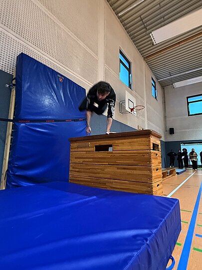 Schüler klettert über einen Kasten mit Weichbodenmatte beim Sportfest