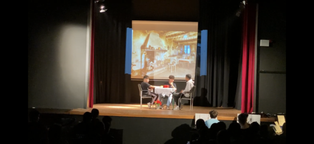 Bühnenszene am gedeckten Tisch vor projiziertem Innenraum im Theaterstück der 8d