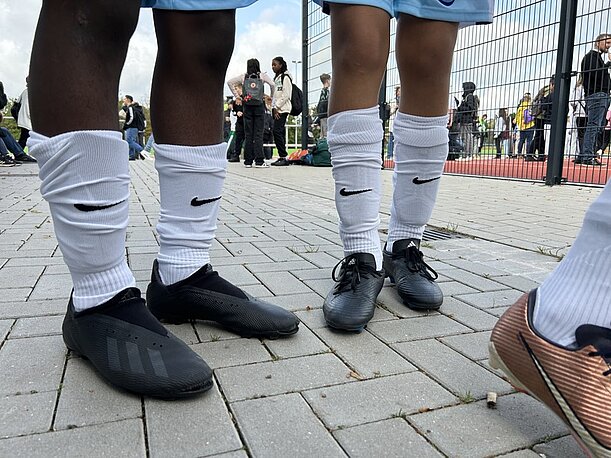 Fußballschuhe und weiße Stutzen von Spielern auf Pflaster