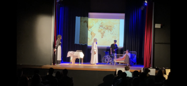 Schlussszene mit Krankenbett und Weltkarte als Projektion im Theaterstück der 8d