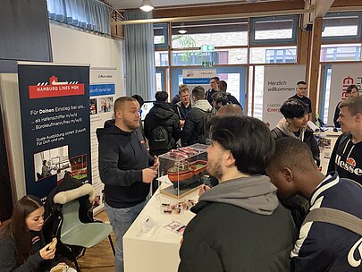 Schüler im Gespräch mit einem Aussteller am Messestand der Hamburger Hafenwirtschaft