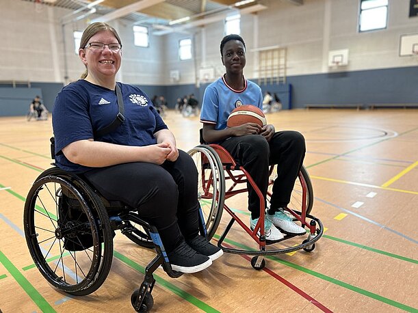Lara von den BG Baskets und Muhamet im Rollstuhl in der Sporthalle