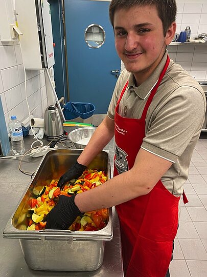 Mohamad Karam mischt in einer Wanne Gemüse für das Curry
