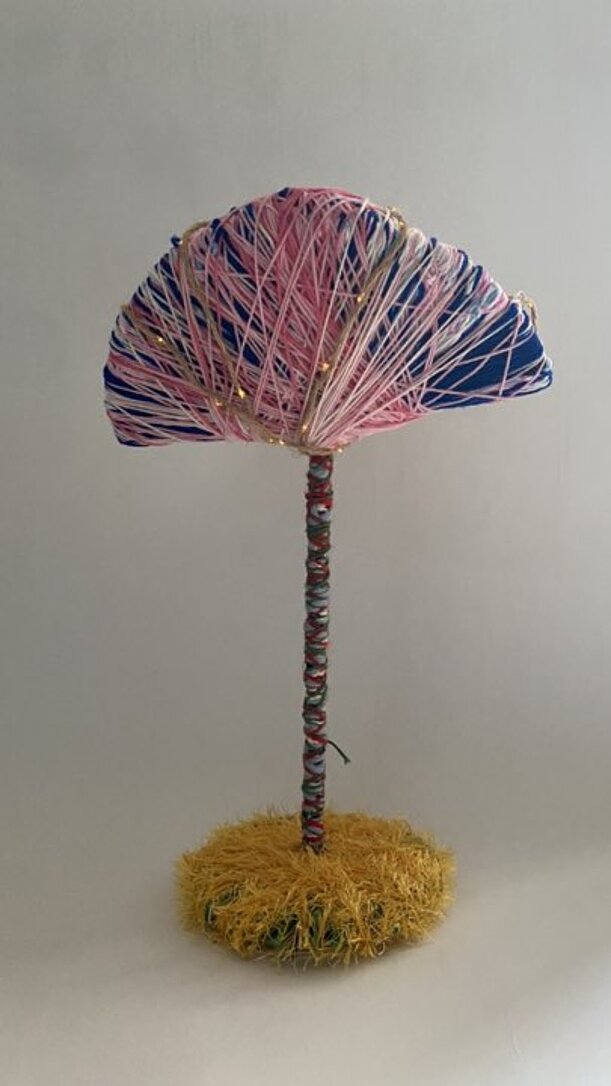 Lampenentwurf mit Schirm aus rosa-blauem Garn auf Stab mit gelbem Sockel