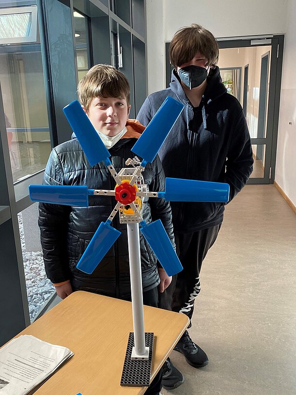 Zwei Schüler mit selbstgebautem Windrad-Modell auf einem Tisch