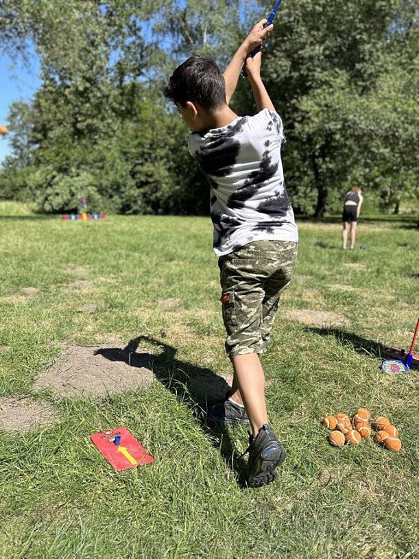 Schüler schlägt beim Cross-Golf auf einer Wiese ab