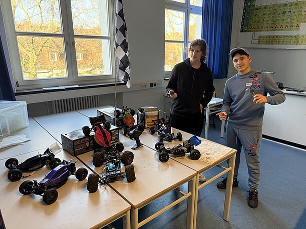 Schüler mit selbst gebauten ferngesteuerten Modellautos im Klassenraum