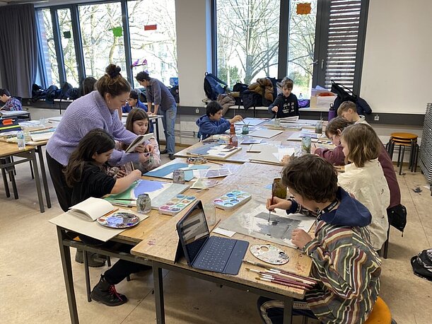 Klasse malt konzentriert an langen Tischen für die Ausstellung im Jenisch Haus