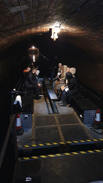 Schülerinnen und Schüler fahren auf einem Boot durch einen unterirdischen Kanal