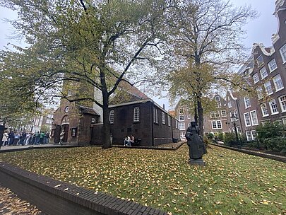 Statue unter herbstlichen Bäumen im Begijnhof in Amsterdam