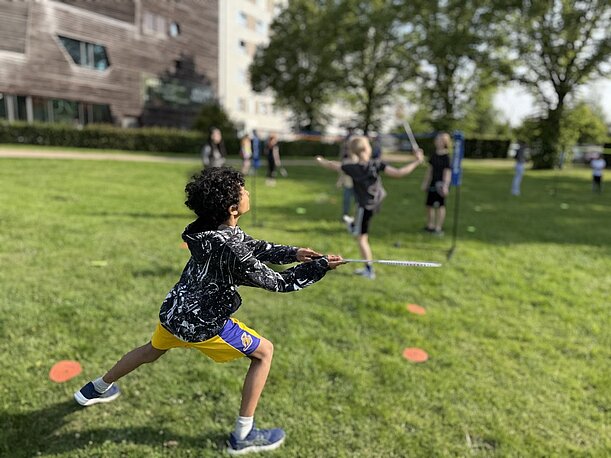Junge wirft beim Sporttag im Inselpark auf der Wiese