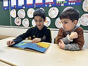 Zwei Jungen schauen bei der Vorlesestunde gemeinsam in ein Bilderbuch