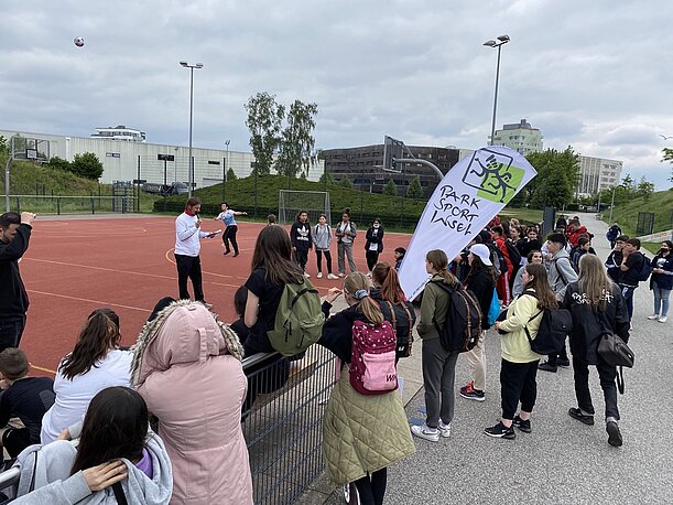 Schülerinnen und Schüler warten am Sportplatz der Park Sport Insel