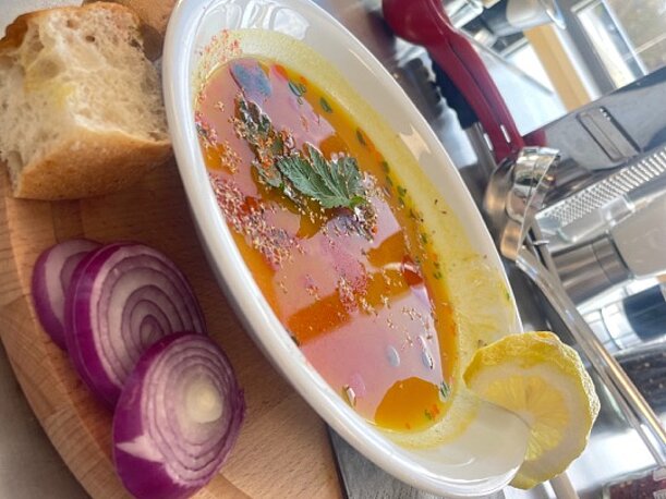 Selbst gekochte Suppe mit Brot und roten Zwiebeln auf einem Holzbrett