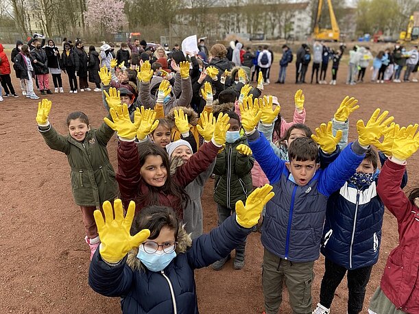 Kinder strecken gelbe Handschuhe in die Luft beim Song gegen Krieg