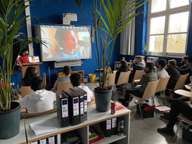 Schülerinnen und Schüler verfolgen im Klassenraum eine digitale Präsentation