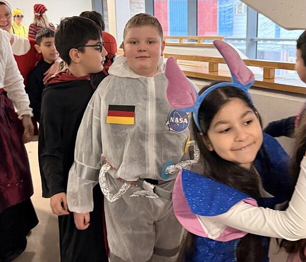 Verkleidete Kinder bei der Polonäse durch den Schulflur zu Fasching