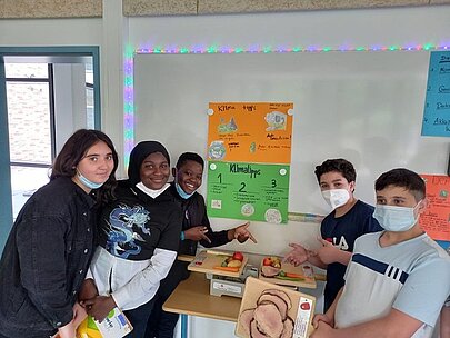 Schülerinnen und Schüler mit Klimaplakat am Präsentationstisch
