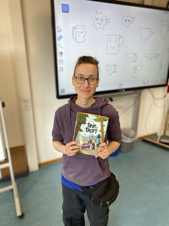 Autorin Josephine Mark mit einem Comicbuch im Klassenraum