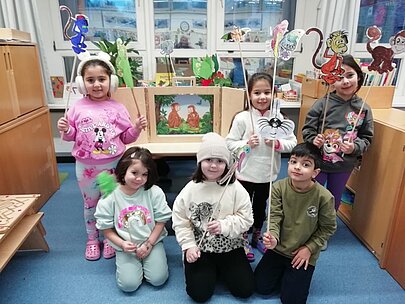 Sechs Kinder mit selbst gebastelten Figuren im Klassenraum nach dem Vorlesewettbewerb