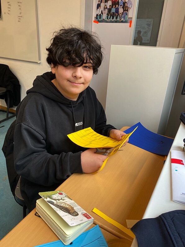 Arin Calcali bastelt am Tisch mit gelbem Papier