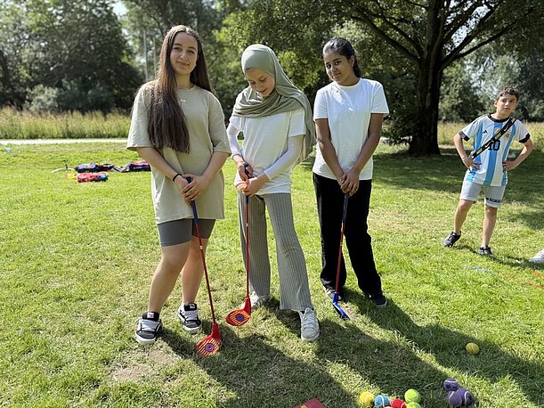 Drei Schülerinnen mit Minigolfschlägern auf der Wiese