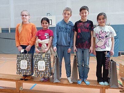 Fünf Grundschulkinder mit Geschenktüten auf einer Bank in der Turnhalle bei Like a Star