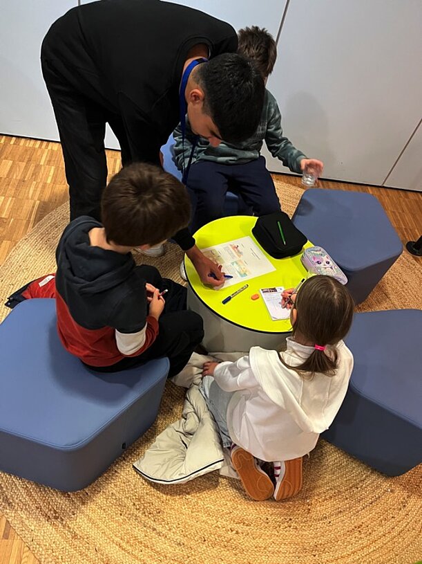 Kinder knobeln auf Sitzkissen an einem niedrigen Tisch beim Mathe-Oscar