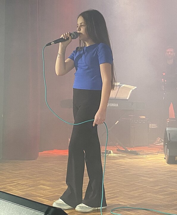 Ajana singt mit Mikrofon auf der Bühne bei The Voice of Wilhelmsburg