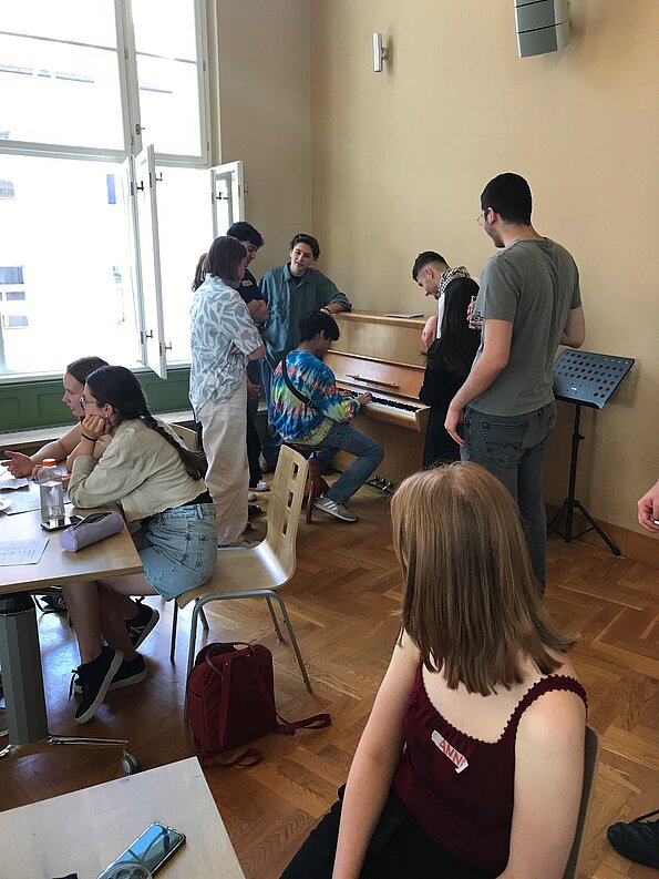 Jugendliche hören einem Klavierkonzert im Klassenraum des Prager Gymnasiums zu